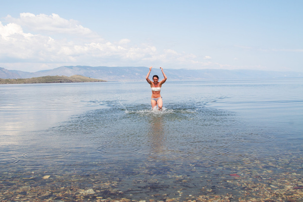 Beautiful young girl bathes in the clear water of Lake Baikal - Фото, зображення