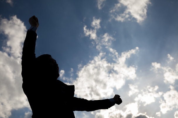 Silueta de hombre de negocios feliz levantando brazos contra el cielo azul
 - Foto, imagen