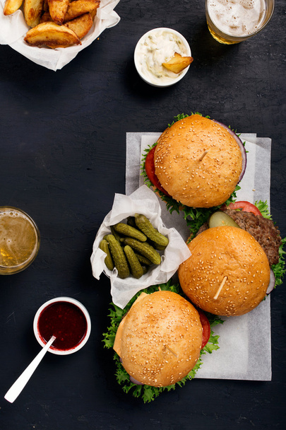 Hamburgers and cheeseburger on dark surface with lager and fries - Foto, immagini