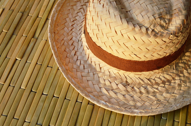 woven hat on bamboo floor in sunshine day - Fotografie, Obrázek