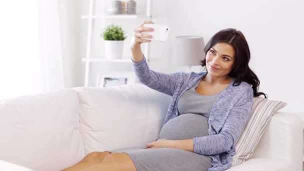 pregnant woman taking selfy by smartphone at home - Filmati, video