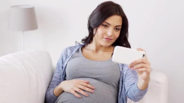 pregnant woman taking selfy by smartphone at home - Materiaali, video