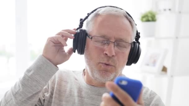 Happy senior man with smartphone and headphones - Záběry, video