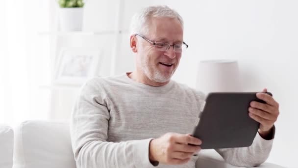 Senior man having video call on tablet pc at home - Filmati, video