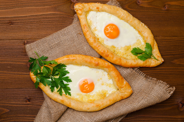 Dos pastel abierto con queso y huevos en una mesa de madera con saqueo
 - Foto, imagen