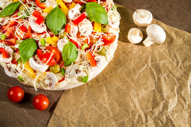 Primer plano de pizza fresca acostada en el papel de hornear
 - Foto, Imagen