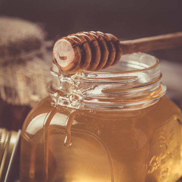 Golden honey in glass jar with dipper - Foto, imagen