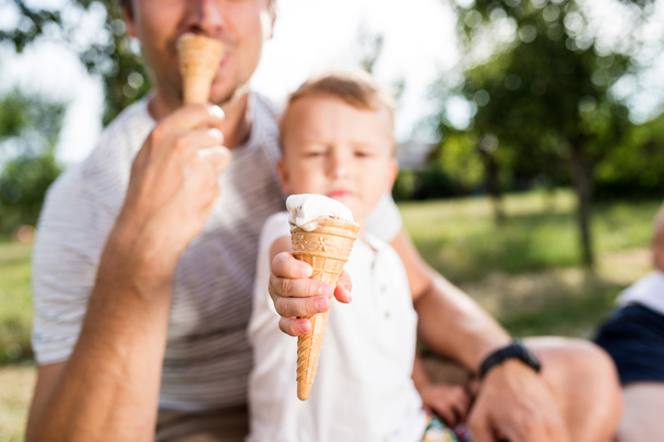 Father and son eating ice cream, sunny summer garden - Fotoğraf, Görsel