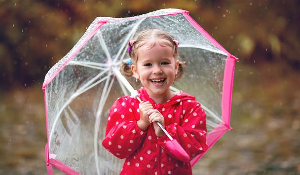 雨の中で傘を持って笑って幸せな子供女の子 - 写真・画像