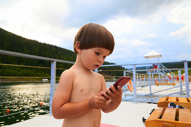 Schattige kleine peuter jongen spelen op zijn smartphone. - Foto, afbeelding