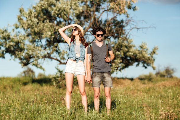 Giovane coppia hipster in piedi contro gli alberi sullo sfondo
 - Foto, immagini