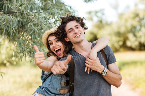 Young happy cheerful couple showing thumbs up and hugging - Foto, Imagem