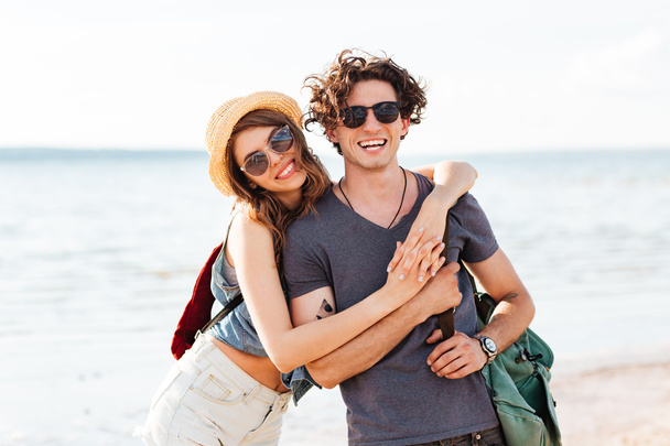 Happy hipster couple standing at the beach and hugging - Fotó, kép