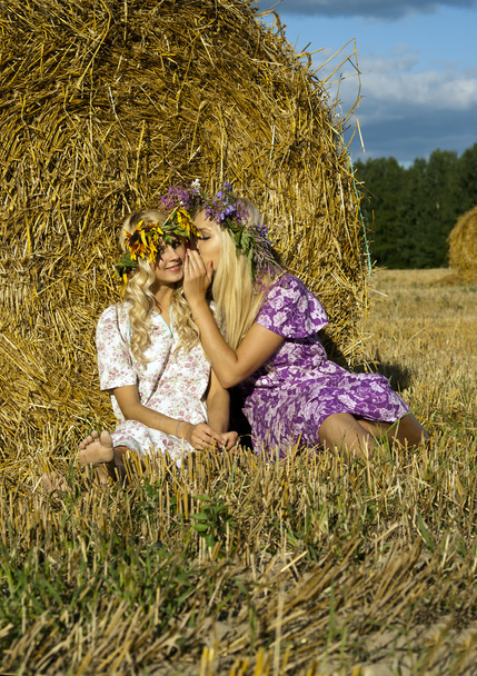 Girl sitting near a haystack in the field - Φωτογραφία, εικόνα