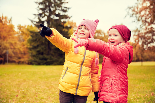 happy little girls pointing finger in autumn park - Fotó, kép