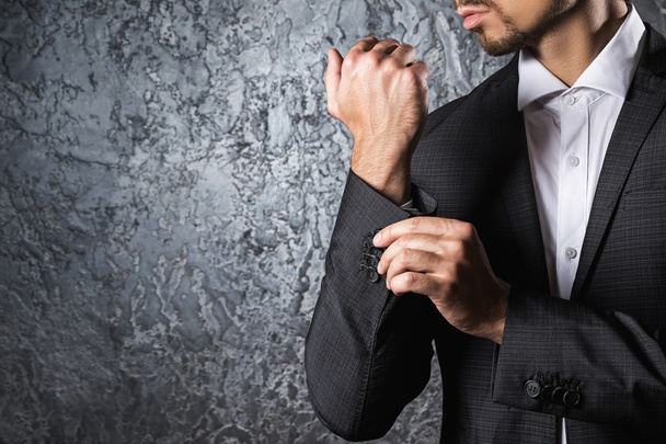 Man in suit buttoning cuff of sleeve - 写真・画像