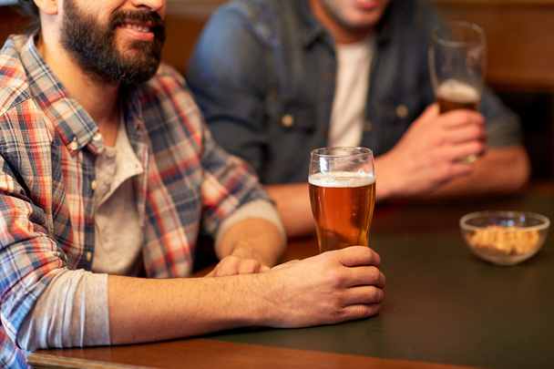 happy male friends drinking beer at bar or pub - 写真・画像