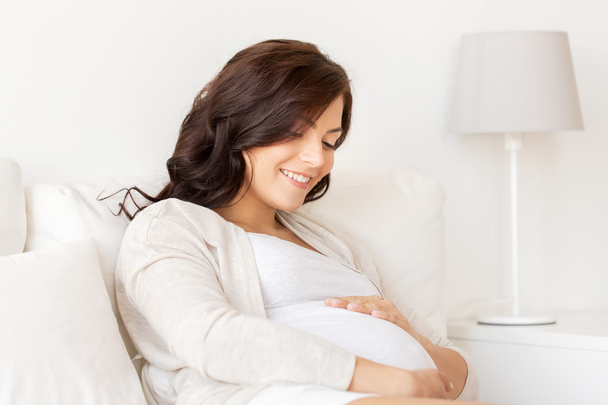 happy pregnant woman lying on bed at home - Photo, Image