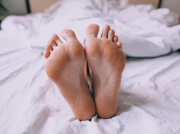 ベッドで人間の足 - 写真・画像