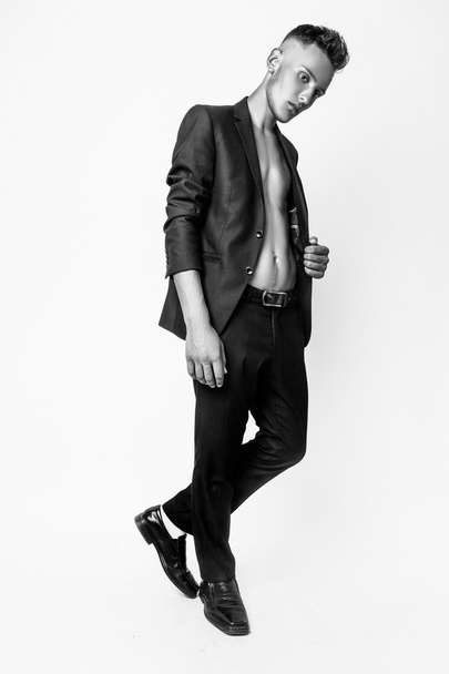 Fashion young businessman black suit casual poses at studio. Black and white - Foto, afbeelding