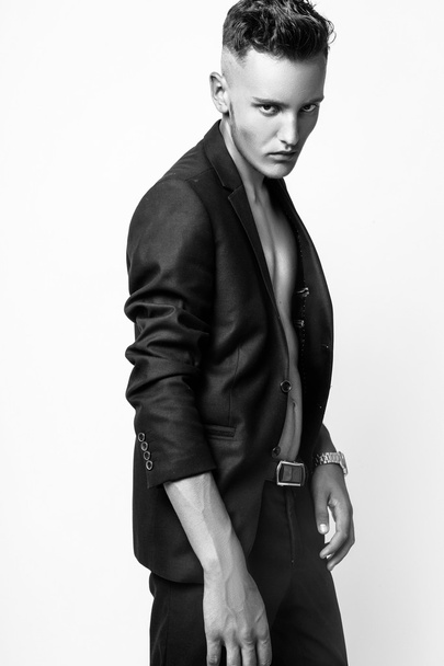 Fashion young businessman black suit casual poses at studio. Black and white - Foto, afbeelding