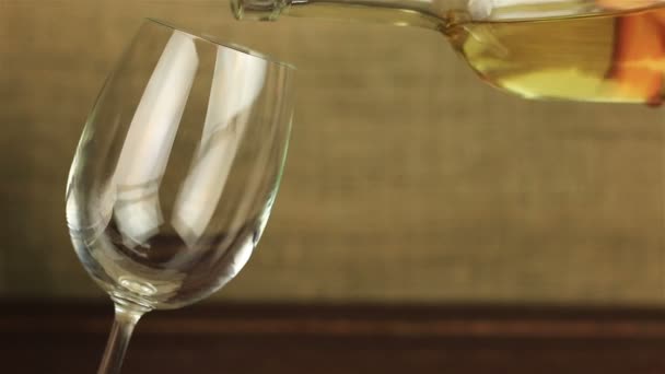 White wine pouring into glass on wooden table - Materiał filmowy, wideo