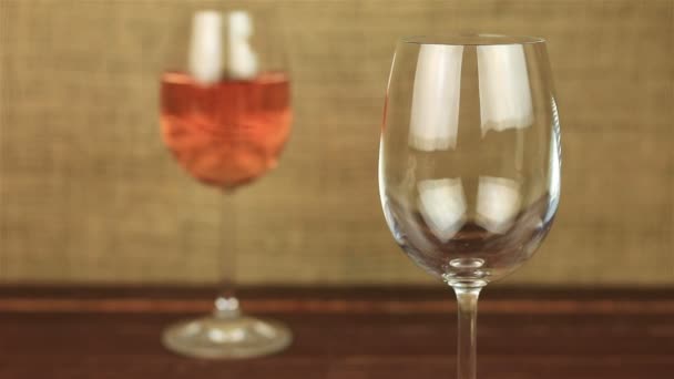 Rose wine pouring into glass on wooden table - Materiał filmowy, wideo
