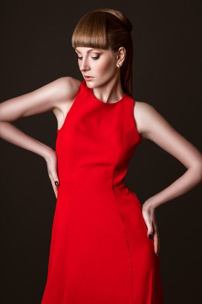 beautiful woman model posing in simple elegant red dress in the studio on black background - Фото, изображение