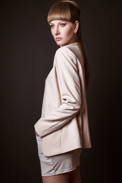 beautiful woman model posing in simple elegant in a light suit in the studio on black background - Foto, imagen