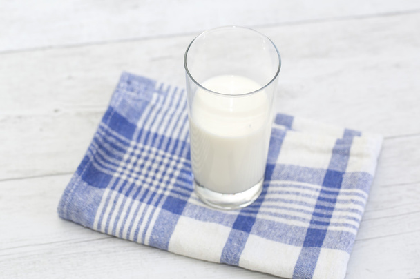 Milk in a glass on a blue checkered napkin - Fotoğraf, Görsel