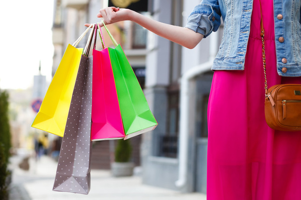 closeup picture of multi colored shopping bags with a hand - Photo, image