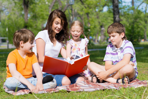 teacher reads a book to children in a summer park - Foto, Imagem