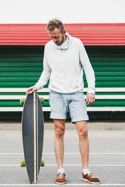 Young man standing with longboard  - Φωτογραφία, εικόνα