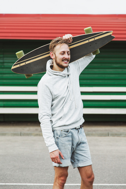 Man with longboard on shoulder - Photo, Image