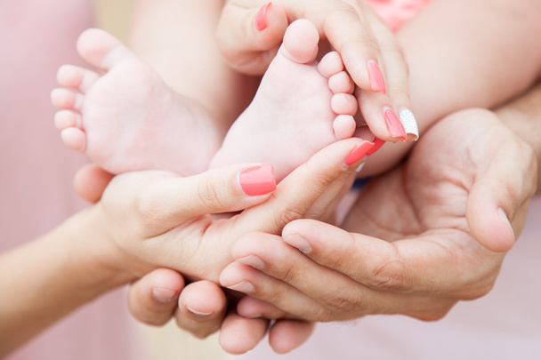 τα χέρια των μαμάδες και μπαμπάδες κρατήστε τα πόδια του μωρού - Φωτογραφία, εικόνα