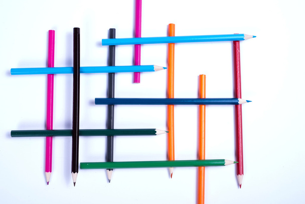 πολύχρωμα μολύβια που διοργανώνονται σε μια γεωμετρική μορφή στον λευκό λεμονάτα - Φωτογραφία, εικόνα
