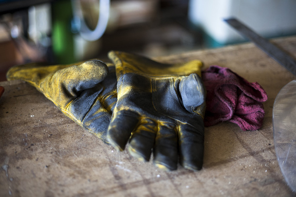 Λερωμένη συγκόλλησης γάντια ανάπαυσης στον πάγκο εργασίας ως εργάτης διαλείμματα για το μεσημεριανό γεύμα. - Φωτογραφία, εικόνα