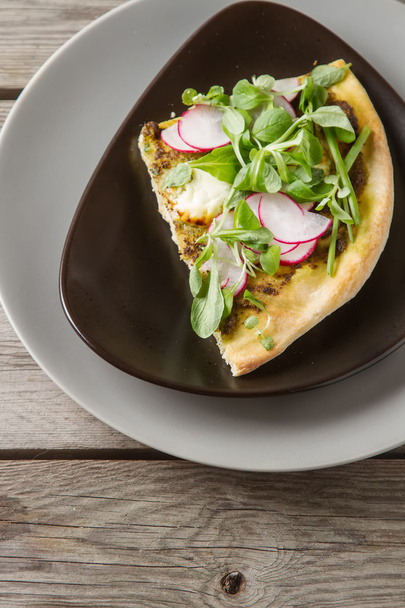 Home Italian pizza with pesto, lettuce and radish on gray plate. - Foto, afbeelding