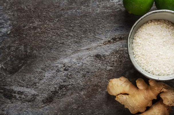 Fresh ginger with a cup of raw white rice, ripe lime green. Grey - Foto, Bild