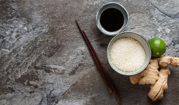 Fresh ginger with a cup of raw white rice, ripe green lime, soy  - Fotoğraf, Görsel