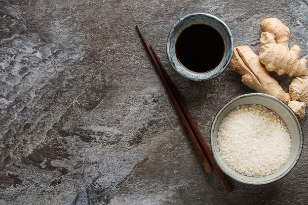Verse gember met een kopje van rauwe witte rijst, rijpe groene limoen, soja  - Foto, afbeelding