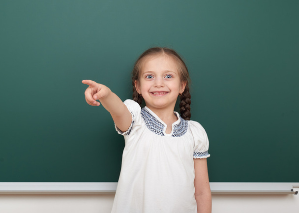 school student girl posing at the clean blackboard, grimacing and emotions, dressed in a black suit, education concept, studio photo - Foto, immagini