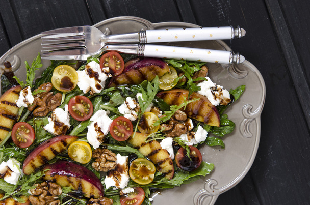 Salad with arugula and cherry tomatoes feta peaches with balsamic cream   - Photo, Image