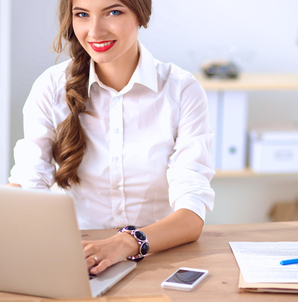 Attractive businesswoman sitting  on desk in the office - Foto, imagen