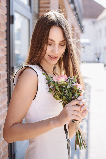Young girl walking on city street with bouquet - Zdjęcie, obraz