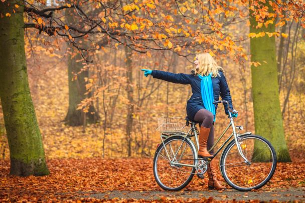 Active woman riding bike in autumn park. - Fotoğraf, Görsel