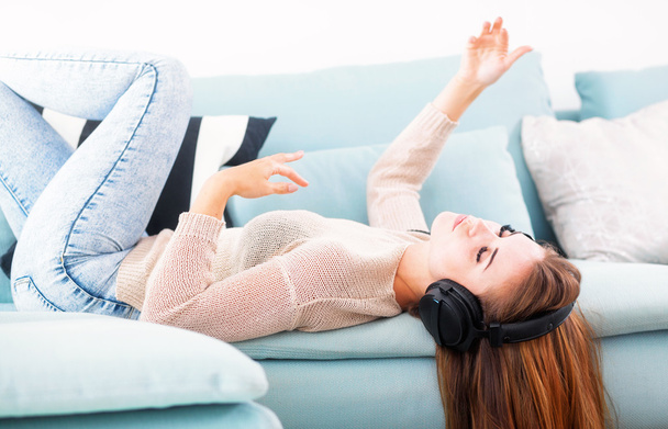 Woman with headphones lying and listening to music at home - Foto, imagen