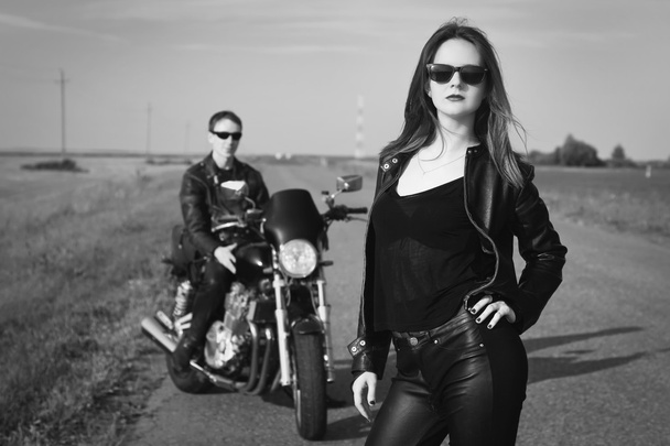 Байкер и девушка стоят на дороге
 - Фото, изображение