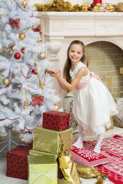 Little girl in  beautiful dress decorates the Christmas tree  - 写真・画像