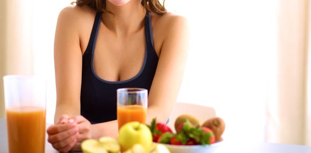 Girl sitting in the kitchen on the desk with fruit and glasses with juice - Foto, Imagem